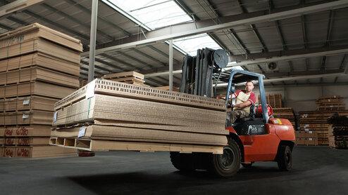 Gabelstapler transportiert Holz und Holzpaletten in Lager
